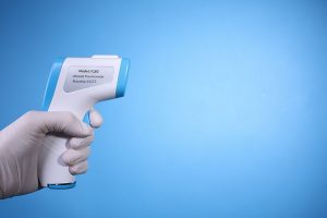 800px-Hand_with_gloves_holding_non-contact_infrared_thermometer_on_blue_background_with_copy_space